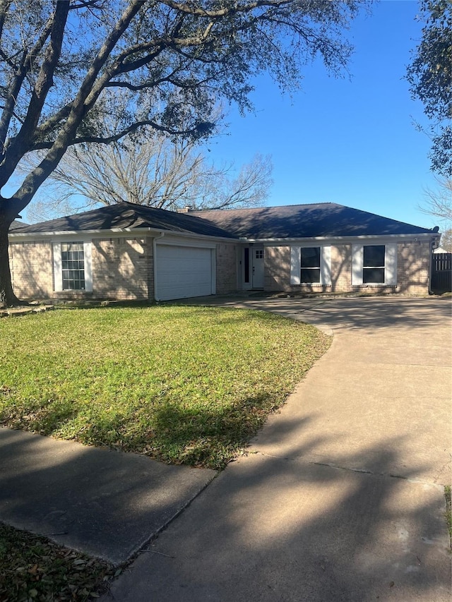 ranch-style home with an attached garage, concrete driveway, brick siding, and a front yard