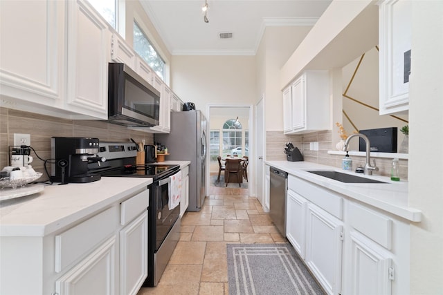 kitchen featuring stainless steel appliances, a sink, visible vents, ornamental molding, and stone tile flooring