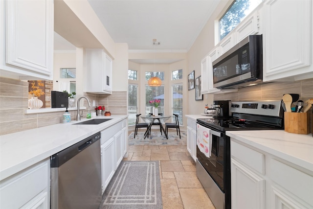 kitchen with stainless steel appliances, tasteful backsplash, a sink, and stone tile flooring