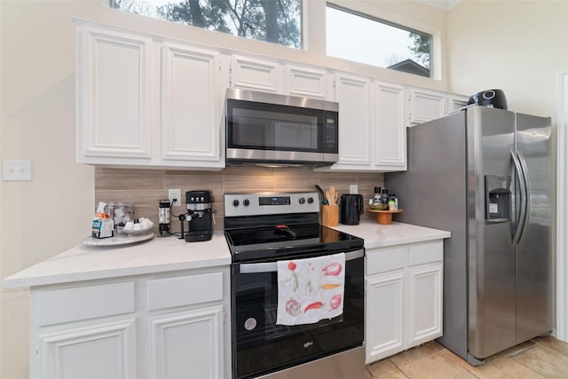 kitchen featuring stainless steel appliances, backsplash, and white cabinets