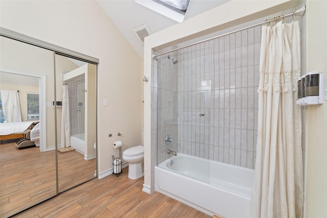 ensuite bathroom with vaulted ceiling with skylight, connected bathroom, toilet, wood finished floors, and shower / bath combo