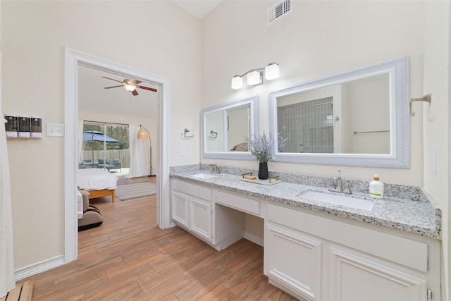 ensuite bathroom with double vanity, visible vents, a sink, and wood finished floors