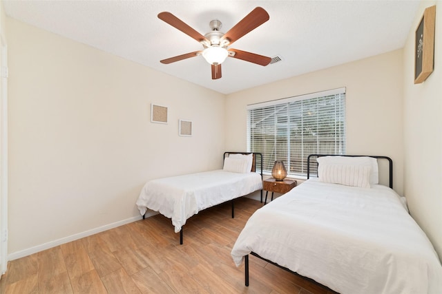 bedroom with light wood finished floors, baseboards, visible vents, and a ceiling fan