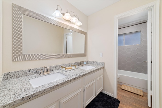 full bath featuring double vanity, a sink, toilet, and wood finished floors