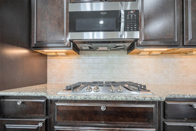 kitchen with stainless steel appliances, dark brown cabinetry, light stone counters, and tasteful backsplash