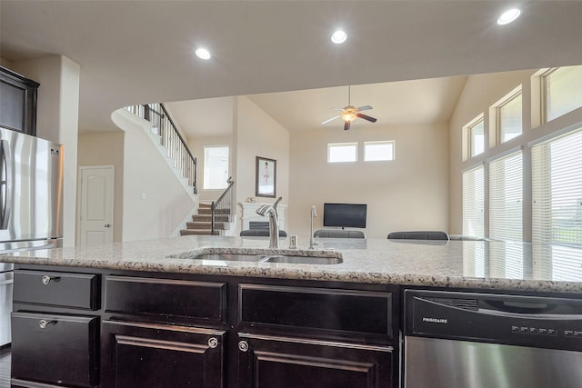 kitchen featuring light stone counters, recessed lighting, appliances with stainless steel finishes, open floor plan, and a sink