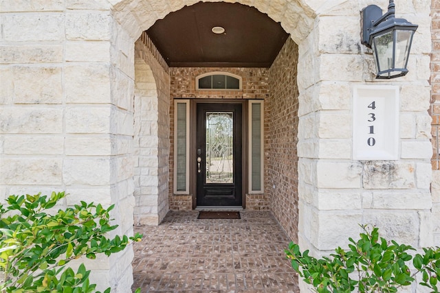 doorway to property with stone siding and brick siding