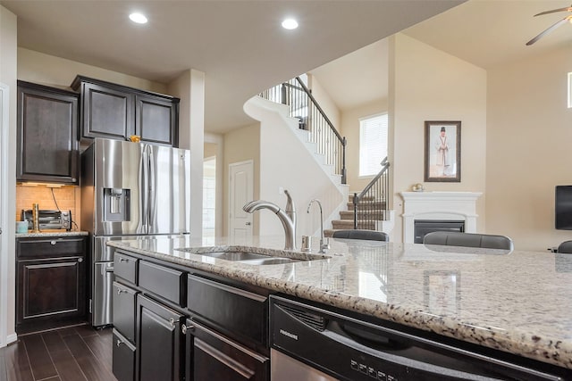 kitchen featuring dark wood-style floors, decorative backsplash, a glass covered fireplace, a sink, and dishwasher