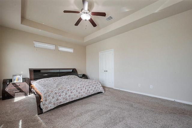 bedroom featuring baseboards, visible vents, a tray ceiling, and carpet flooring