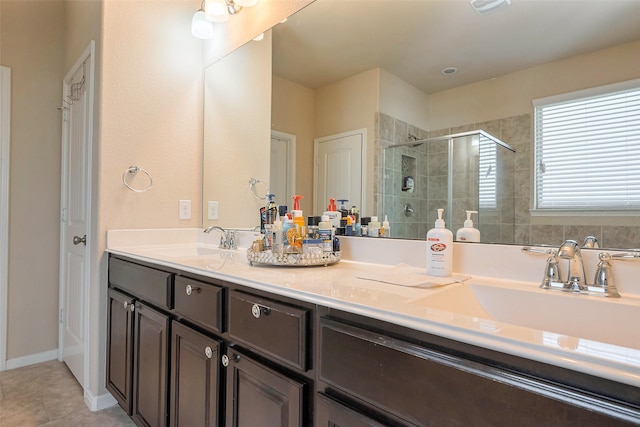 bathroom featuring double vanity, a shower stall, a sink, and tile patterned floors