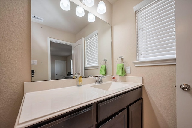 bathroom featuring a textured wall, visible vents, and vanity