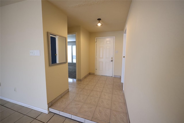 hallway featuring light tile patterned floors and baseboards