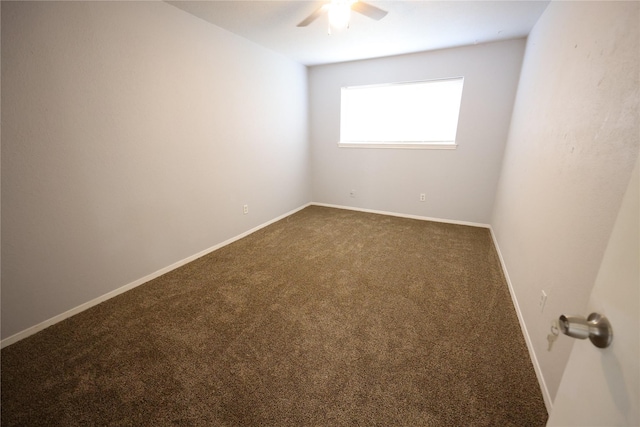 unfurnished room with baseboards, dark carpet, and ceiling fan