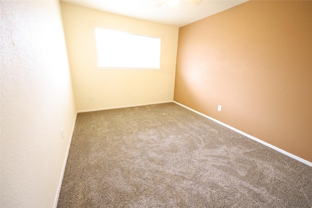 carpeted spare room featuring a ceiling fan and baseboards