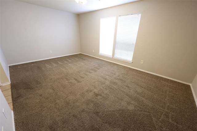 spare room featuring carpet flooring and baseboards