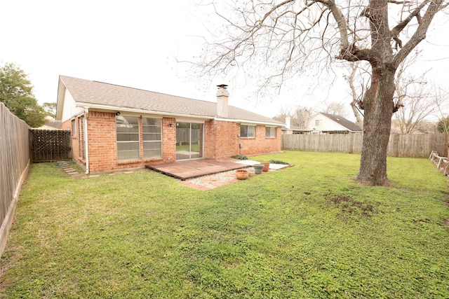 back of house with a chimney, brick siding, a yard, and a fenced backyard