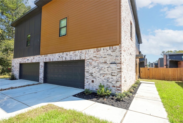 view of side of home featuring a garage, fence, concrete driveway, and brick siding