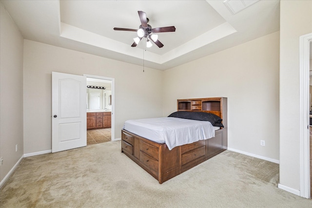 bedroom featuring a raised ceiling, light colored carpet, and baseboards