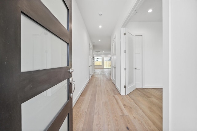 corridor featuring light wood-style flooring, baseboards, and recessed lighting