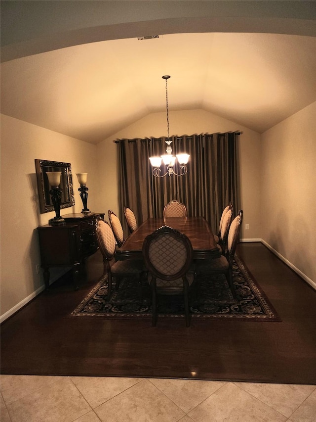 dining room featuring baseboards, visible vents, lofted ceiling, tile patterned floors, and a notable chandelier