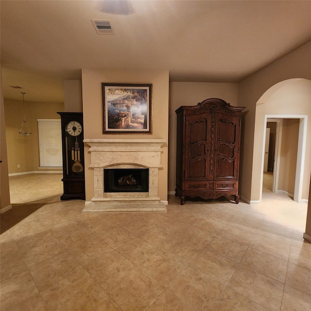 unfurnished living room with baseboards, visible vents, arched walkways, and a high end fireplace