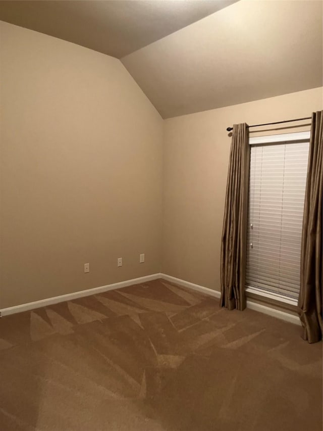 empty room with lofted ceiling, baseboards, and carpet