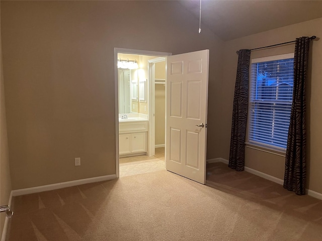 unfurnished bedroom with baseboards, carpet floors, a sink, and connected bathroom