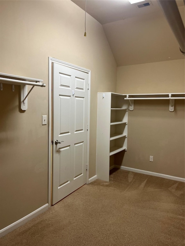 walk in closet with lofted ceiling, carpet flooring, and visible vents