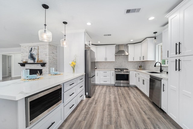 kitchen with stainless steel appliances, visible vents, backsplash, a sink, and wall chimney exhaust hood