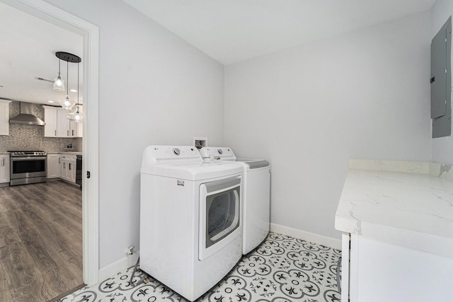 laundry area with washer and clothes dryer, light tile patterned floors, laundry area, electric panel, and baseboards