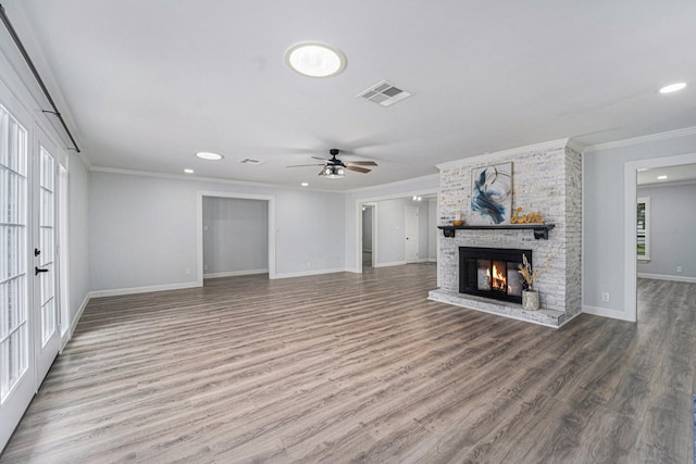 unfurnished living room featuring visible vents, baseboards, wood finished floors, crown molding, and a brick fireplace