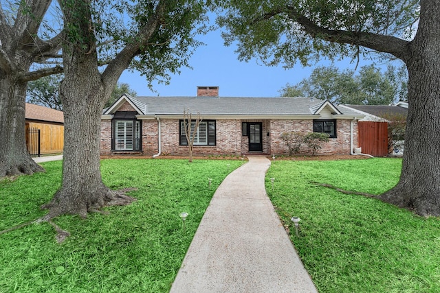 ranch-style home with a chimney, a front yard, fence, and brick siding