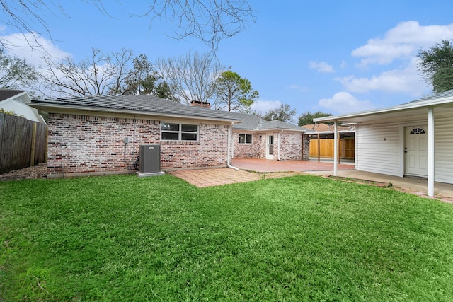 rear view of property featuring a patio area, fence, brick siding, and a lawn