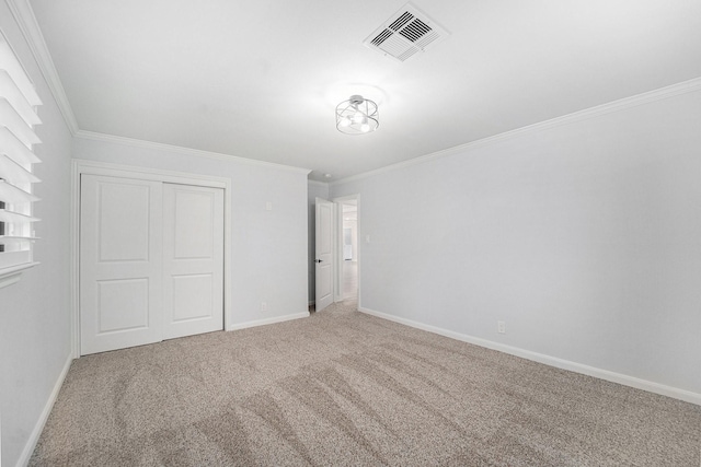 unfurnished bedroom featuring baseboards, visible vents, crown molding, carpet floors, and a closet