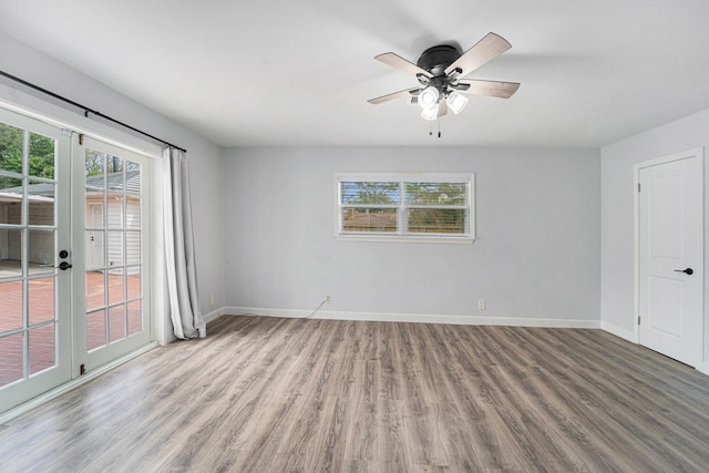 spare room with wood finished floors, a wealth of natural light, and baseboards