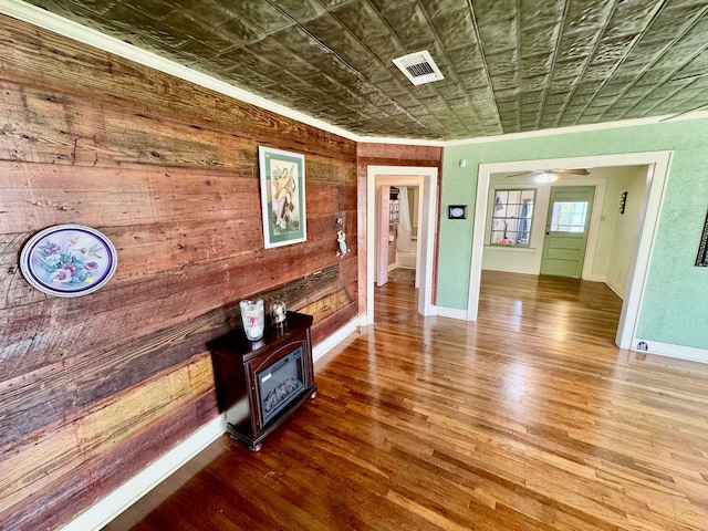 interior space with an ornate ceiling, visible vents, wooden walls, and wood finished floors