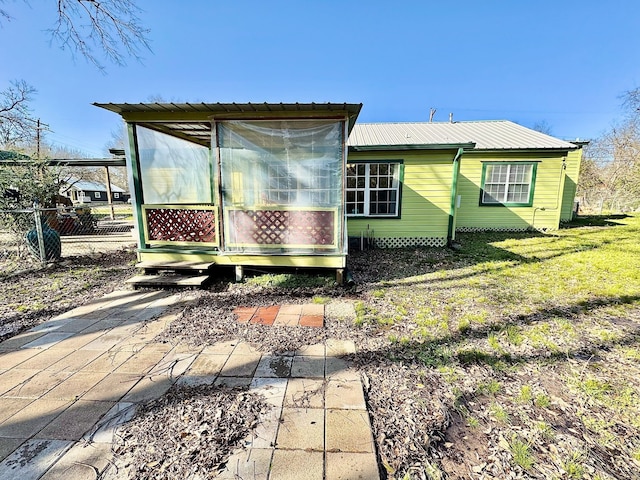 rear view of property featuring fence and metal roof