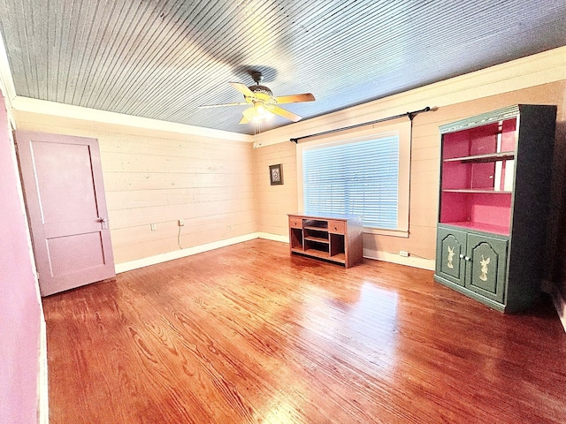 unfurnished room featuring wooden ceiling, wooden walls, a ceiling fan, and wood finished floors