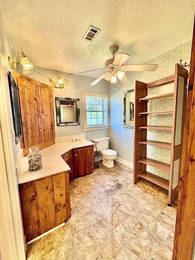 bathroom with toilet, wallpapered walls, visible vents, and a textured ceiling