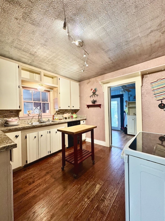 kitchen featuring white range with electric stovetop, white cabinets, dark wood finished floors, a textured wall, and a sink