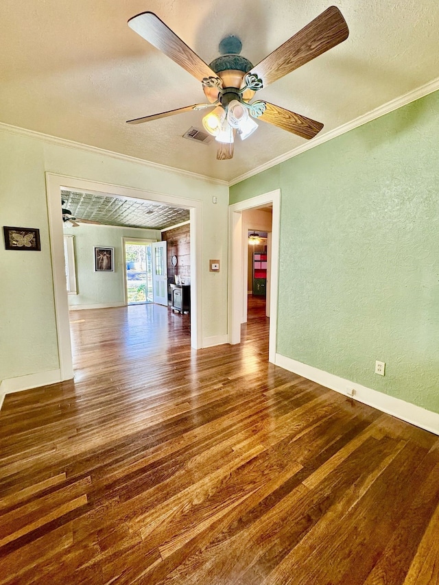 empty room with a textured ceiling, a textured wall, wood finished floors, a ceiling fan, and ornamental molding