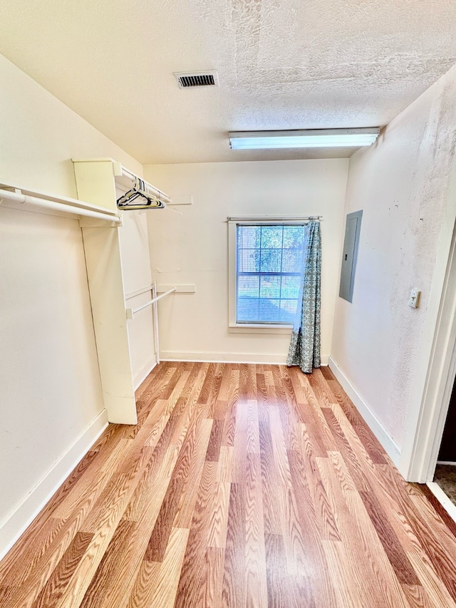 spacious closet with light wood finished floors, visible vents, and electric panel