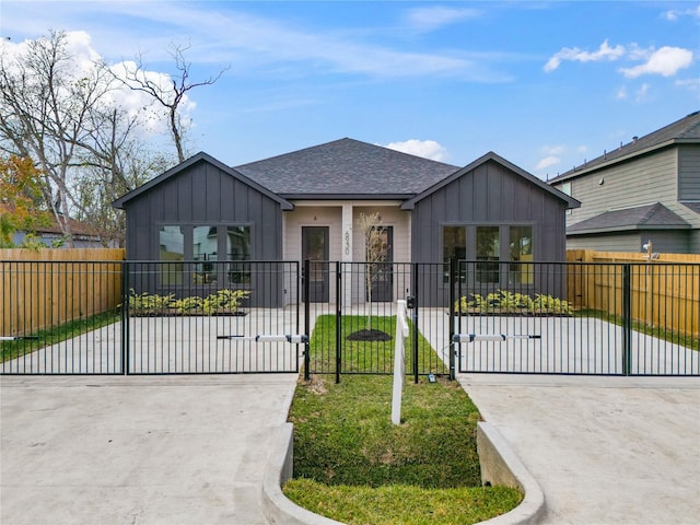 view of front of home with a fenced front yard, a gate, board and batten siding, and roof with shingles