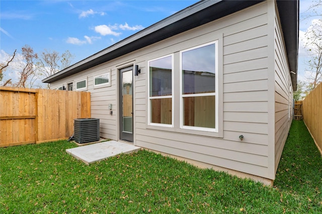 rear view of property with a yard, central AC unit, and a fenced backyard