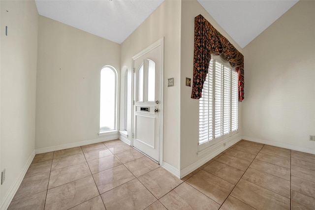 foyer entrance with light tile patterned floors, baseboards, and lofted ceiling