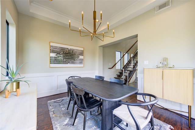 dining area featuring a wainscoted wall, visible vents, a raised ceiling, and wood finished floors