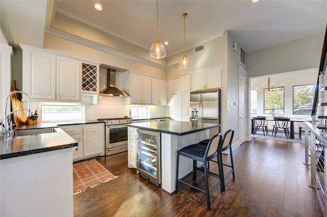 kitchen with beverage cooler, a sink, visible vents, wall chimney range hood, and appliances with stainless steel finishes