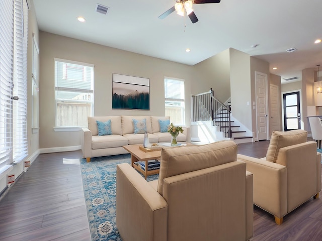 living room featuring visible vents, a healthy amount of sunlight, wood finished floors, and stairs