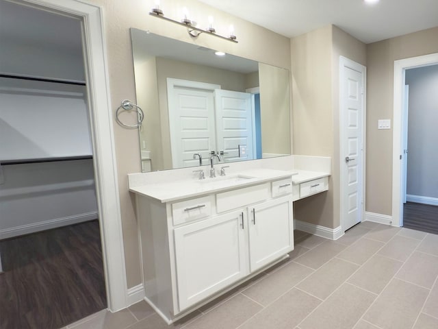 full bath with a walk in closet, baseboards, wood finished floors, and vanity