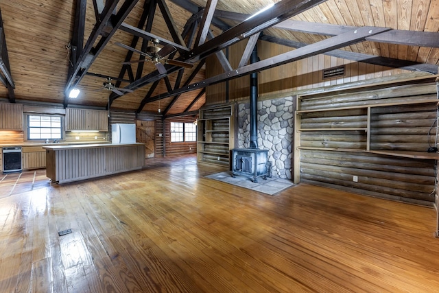 unfurnished living room featuring wood ceiling, a ceiling fan, light wood finished floors, beamed ceiling, and a wood stove